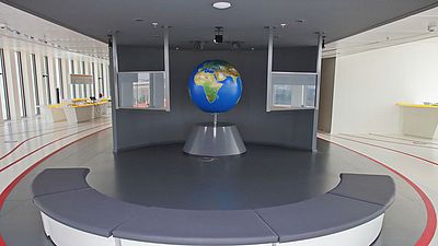 Ausstellungsraum mit einer Weltkugel und verschiedenen Monitoren